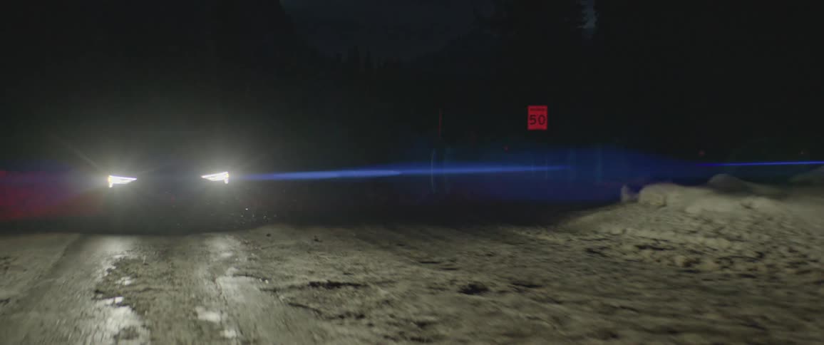 Car drives along icy road bordered by snow turning toward store