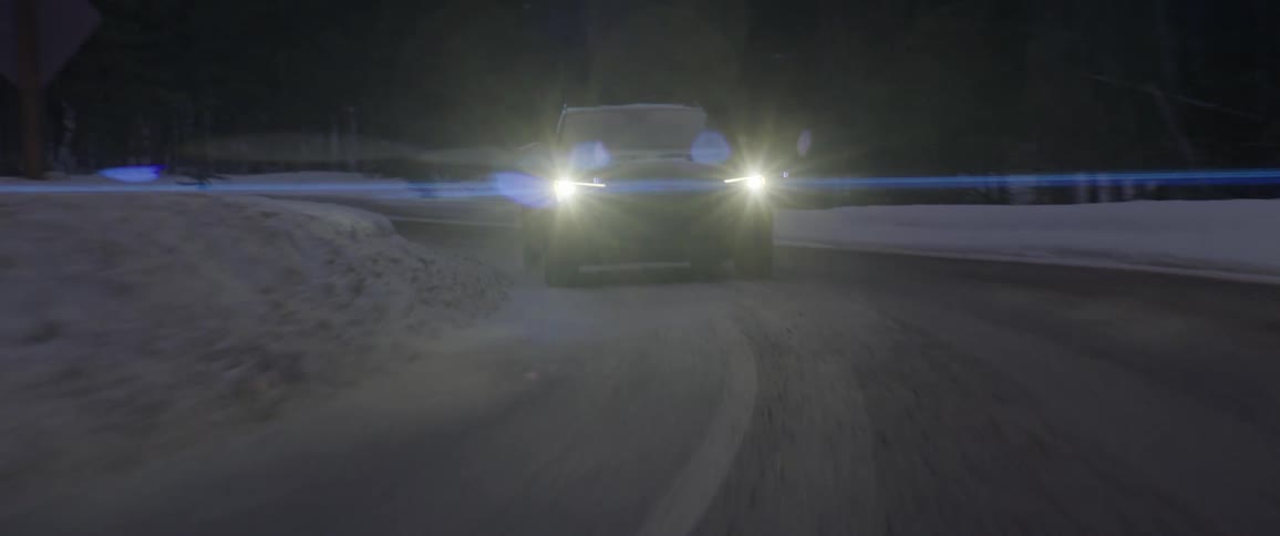 Black car driving on a snow covered road in the countryside at morning