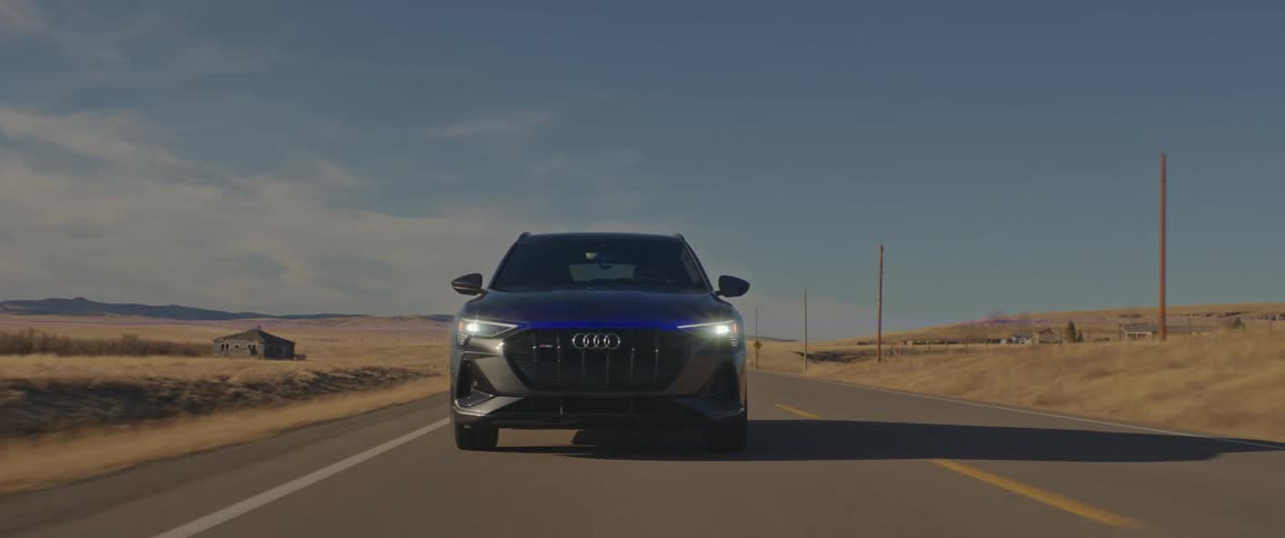 Black luxury car driving on a road in the countryside at morning