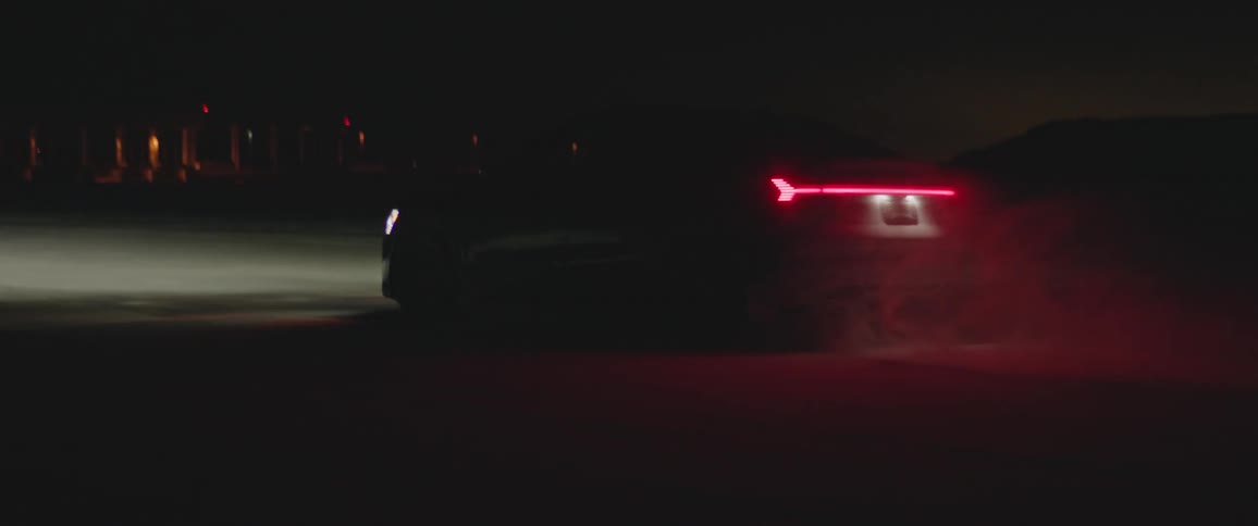 Black sports car with headlights on driving on the countryside at night