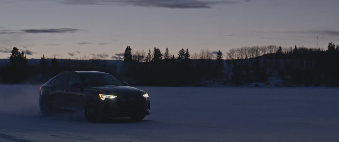 A car is driving in a rural area in winter at dusk