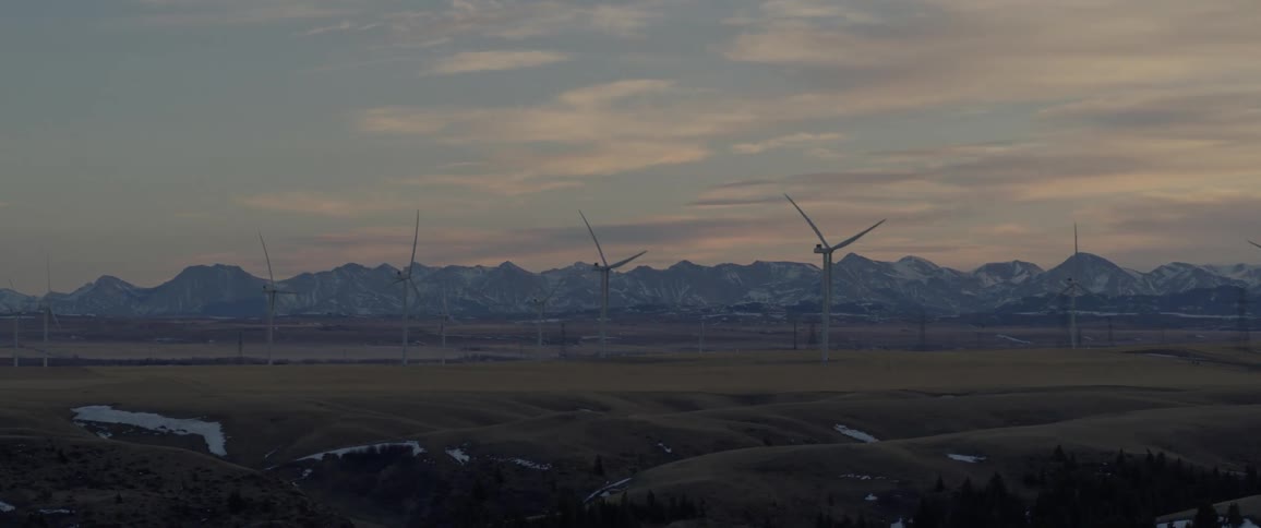 Car driving near a wind farm in the plains at evening