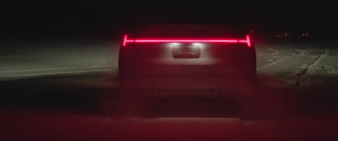 A vehicle speeds through a snow covered field at night