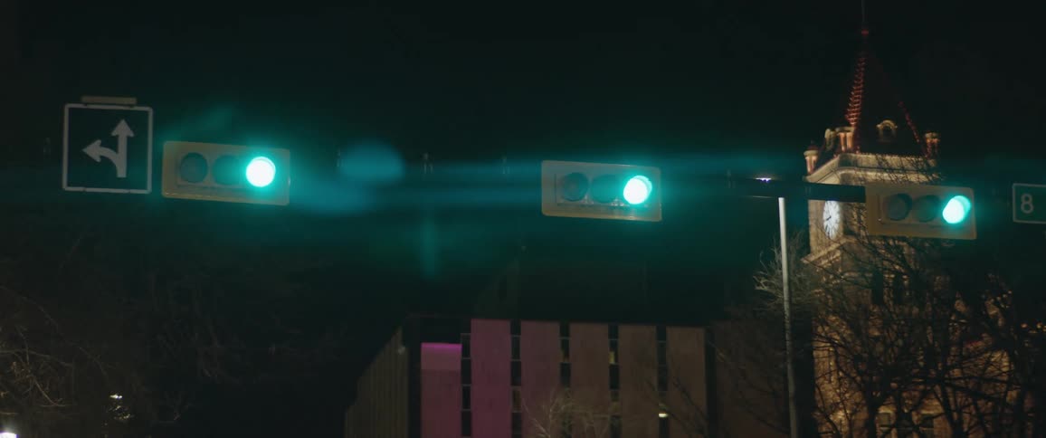 Traffic lights in a city with trees a building and the sky in the background