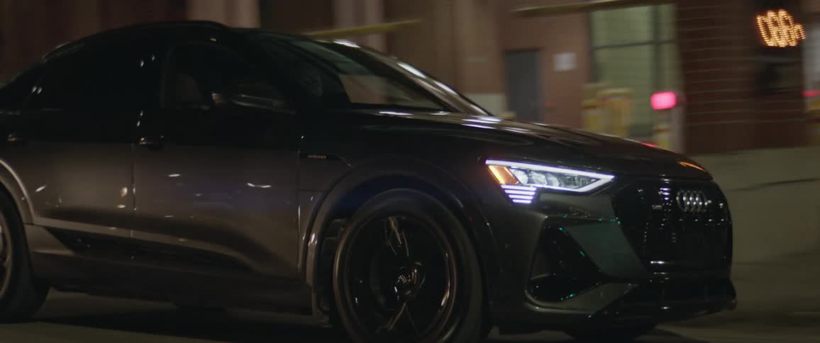 A car is driving down a road in a downtown city at night