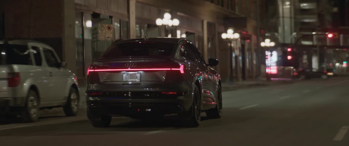 A car is driving on a road in a downtown city at night