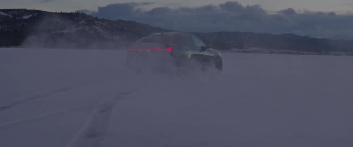 A black car travels on a snow covered road and slides from side to side
