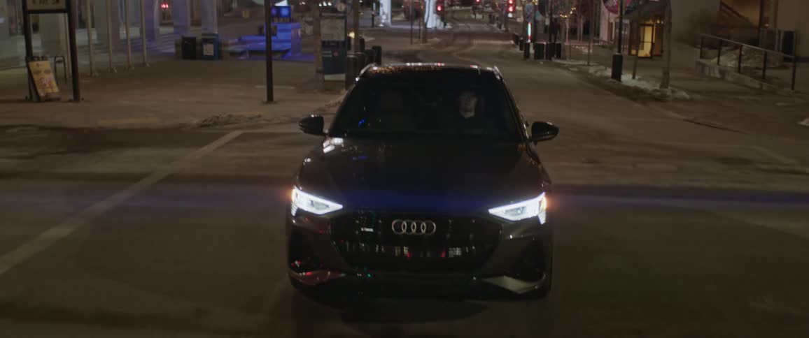 A car is driving through a downtown city in winter