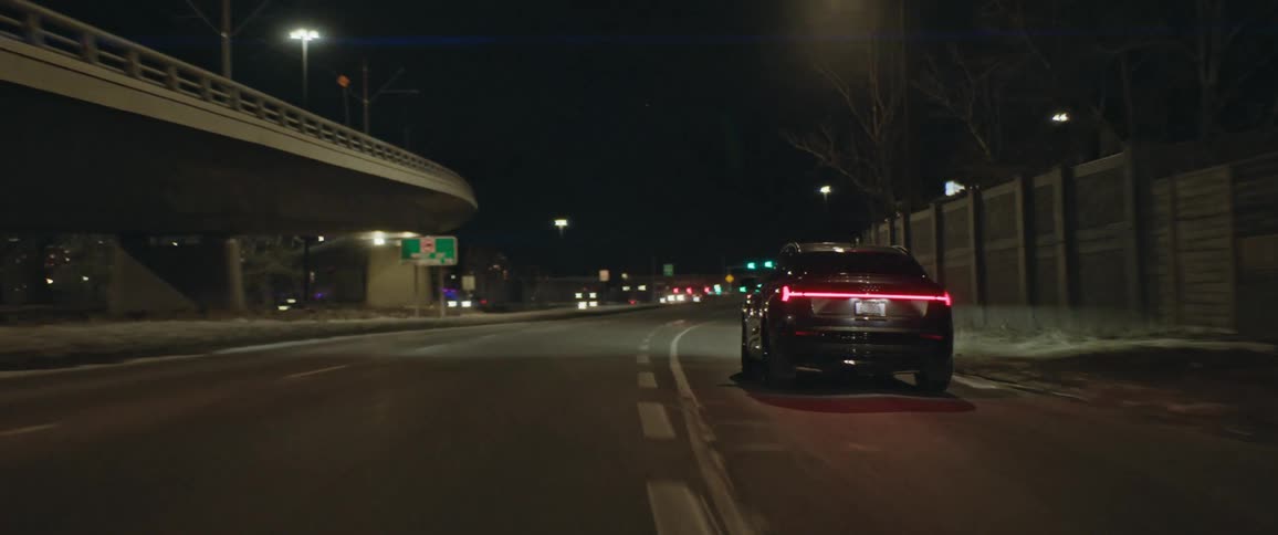 A vehicle driving on a city street with buildings in the background