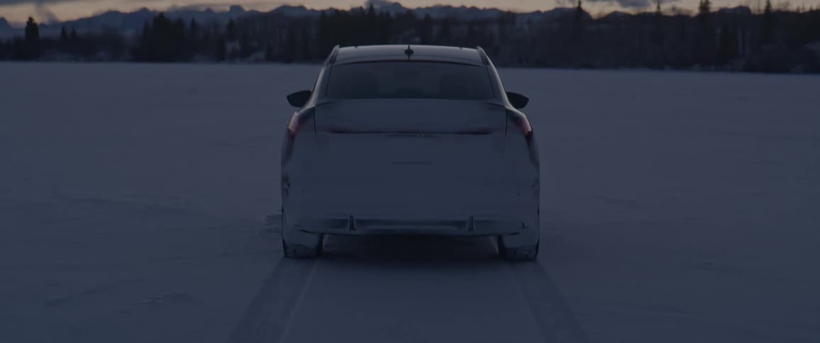 A vehicle on a snowy landscape with trees the sky and clouds in the background