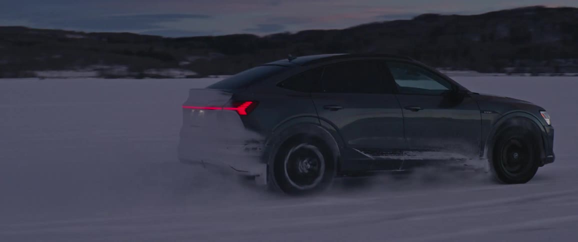Dark grey audi car drives in the snowy field