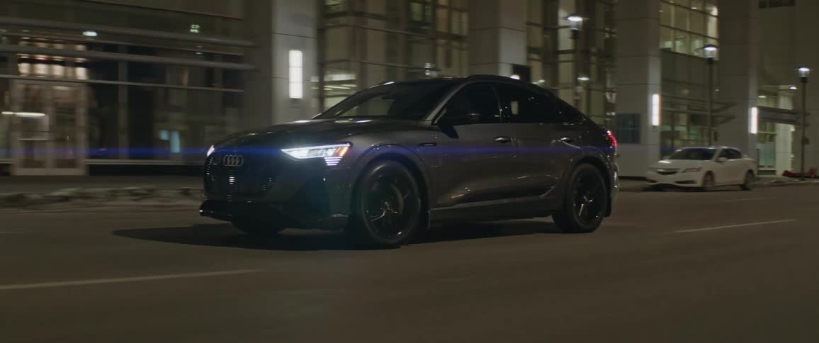 An automobile drives speedily along a city street at nighttime