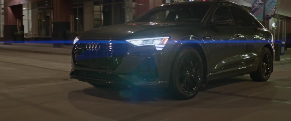 Dark grey audi car travels in the city streets at night