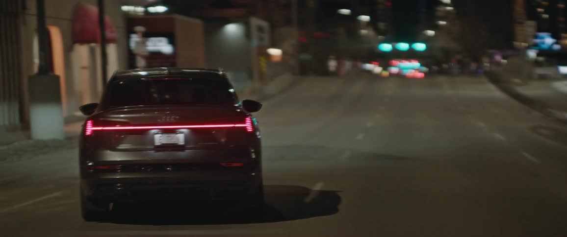 A vehicle driving on a city street with buildings traffic lights and streetlights in the background