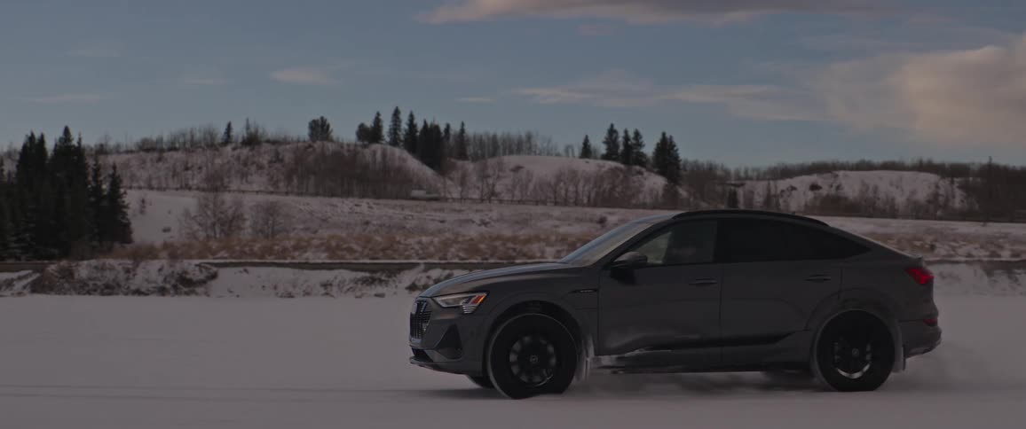 Black car driving on a snow covered plain in the countryside at morning