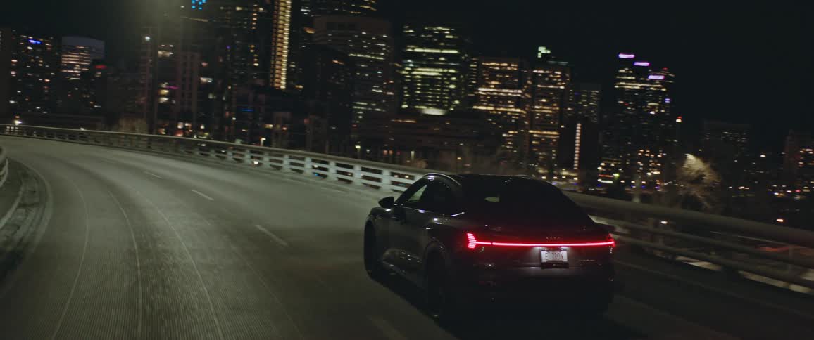 Black sports car driving on the highway near the city downtown at night