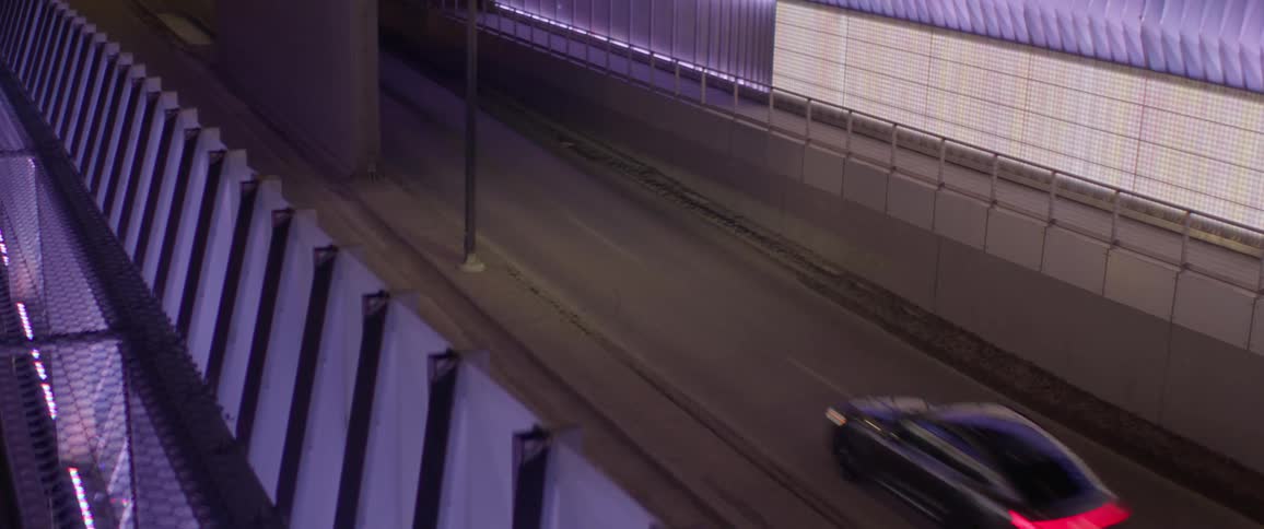 A vehicle driving on a road surrounded by walls and railings