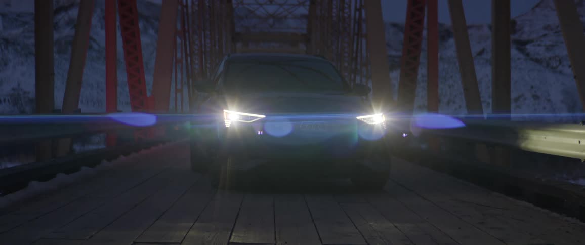 Black car with headlights on parked on a bridge in the mountains at evening