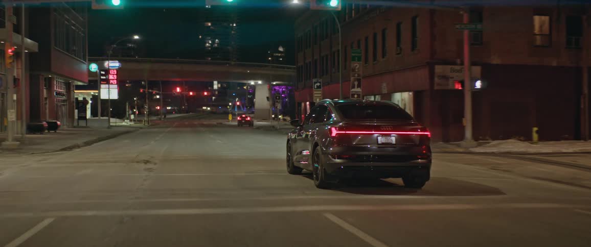 A vehicle driving on a city street with buildings traffic lights and streetlights in the background