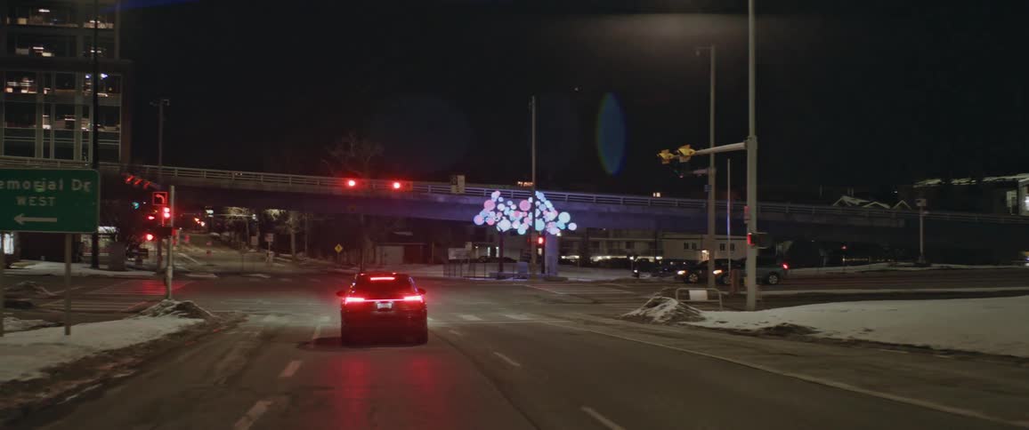 A car drives along a road until reaching a red light and stopping