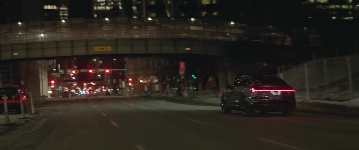 A car travels a city road at night making a left turn and then stopping at a traffic signal