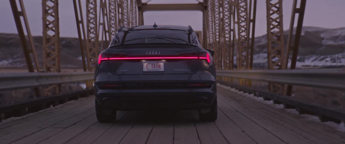 An audi car travels a rural mountainside bridge