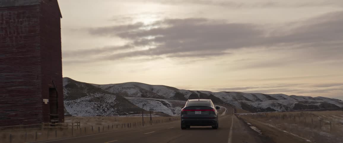 A car drives past a small tower on the side of the road
