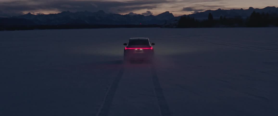 Black car driving on a snow covered desert near the mountains at morning