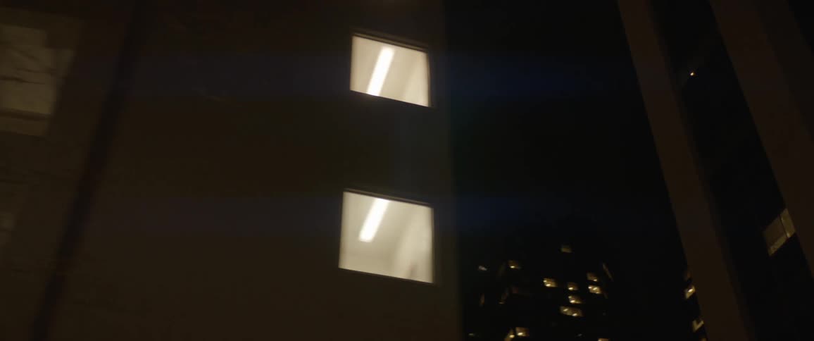 A city with buildings windows and lights with the sky in the background