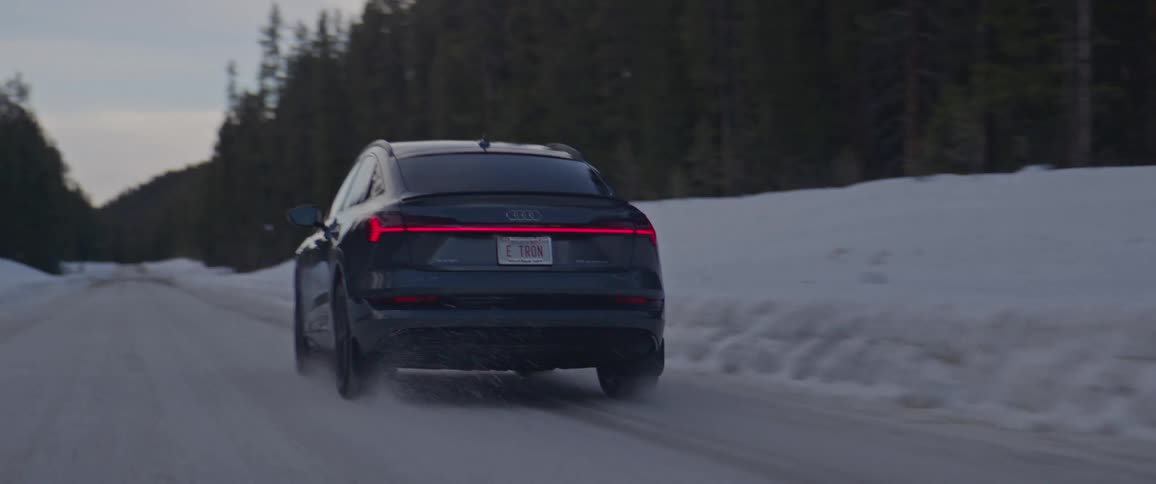 Black car driving on a snow covered road in the countryside at morning
