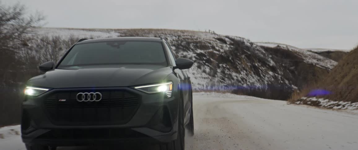 Black car driving on a snow covered road in the countryside at morning