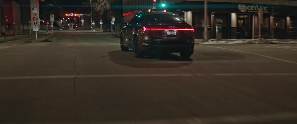 Car drives along city street through intersection toward red stoplight