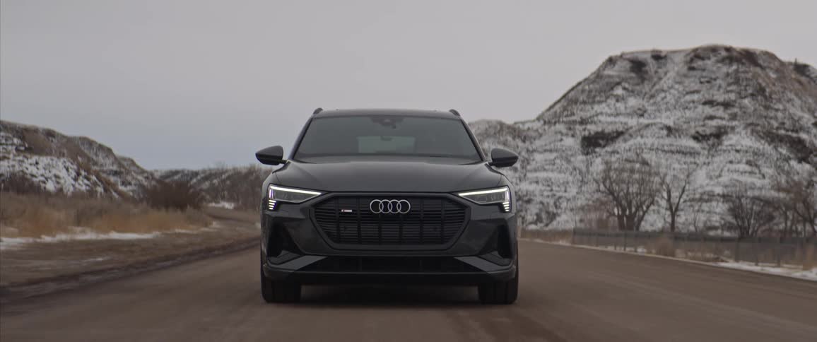 A vehicle driving on a road with a mountain range the sky and clouds in the background