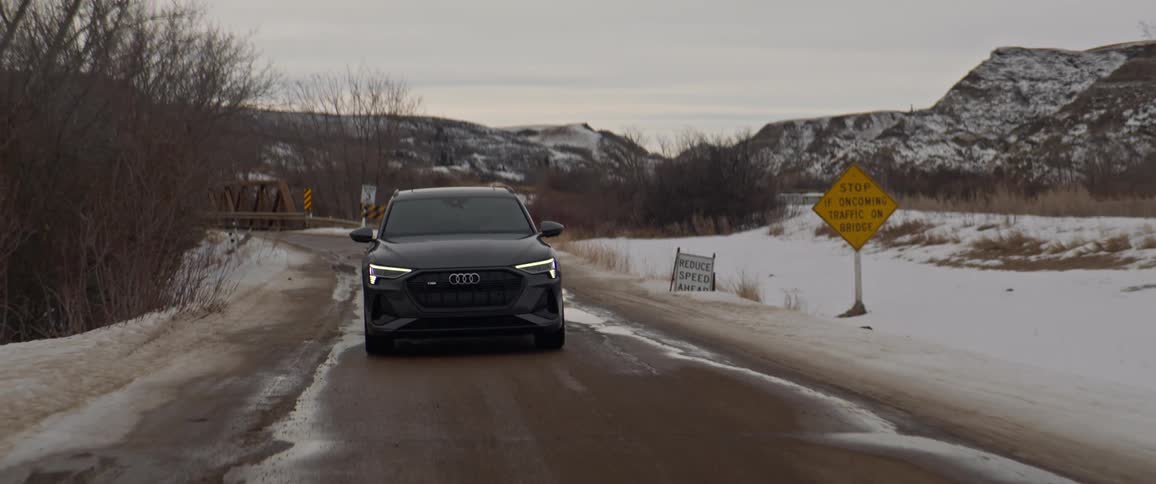 An audi vehicle drives a rural snowy road