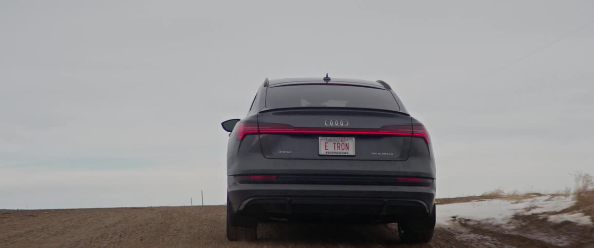 A vehicle driving on a dirt road with trees the sky and clouds in the background