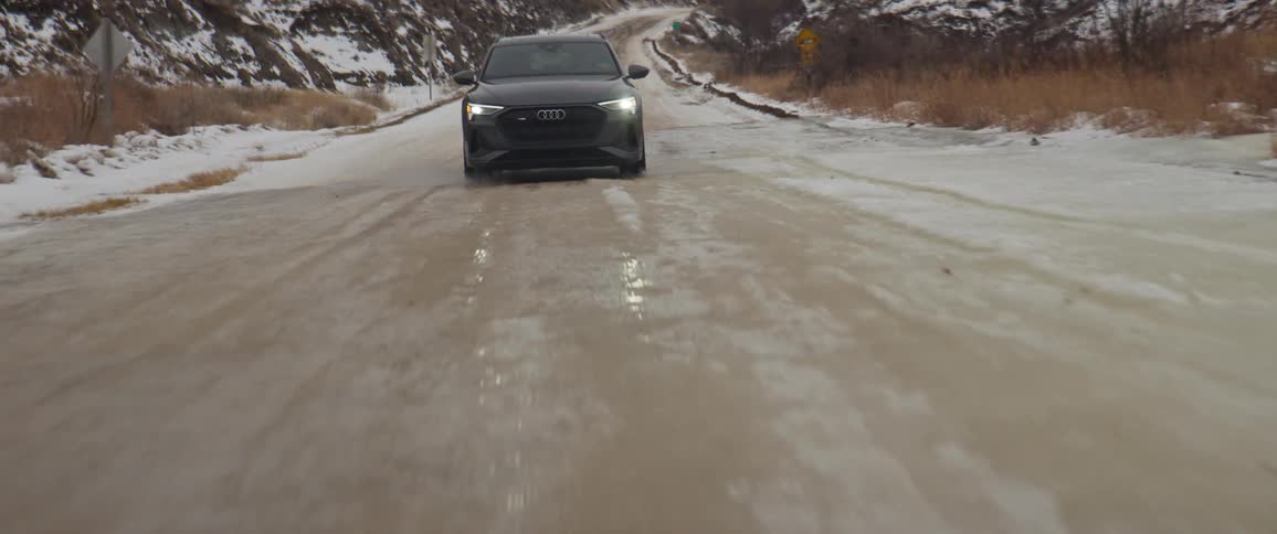 A vehicle descends a road on a slope on a cloudy day