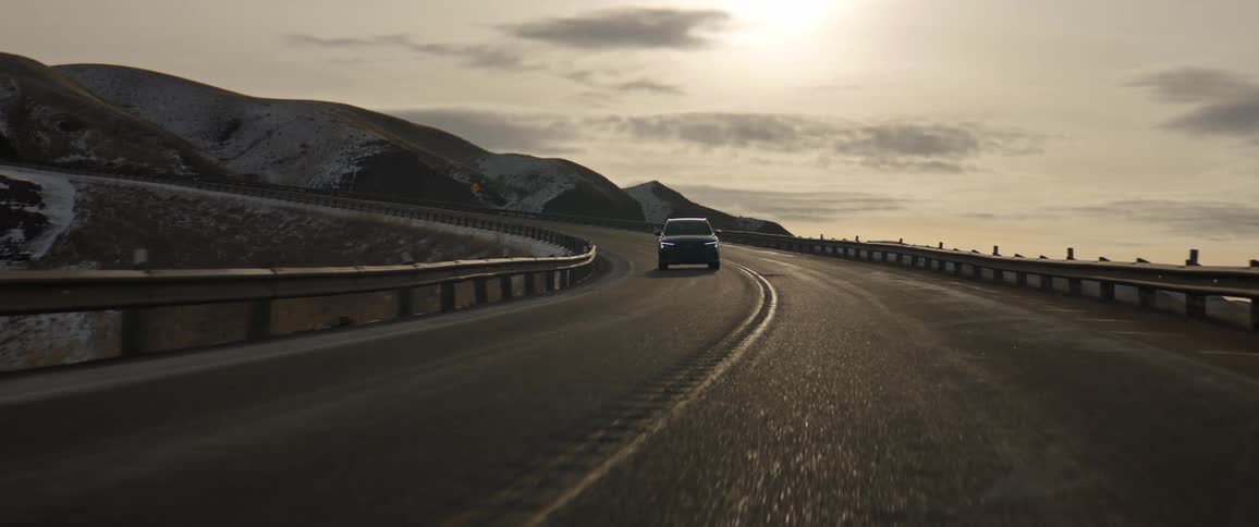 Dark gray audi sport car drives downhill on highway