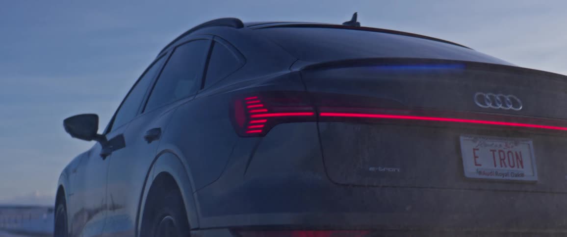 An audi vehicle travels a rural snow dusted road
