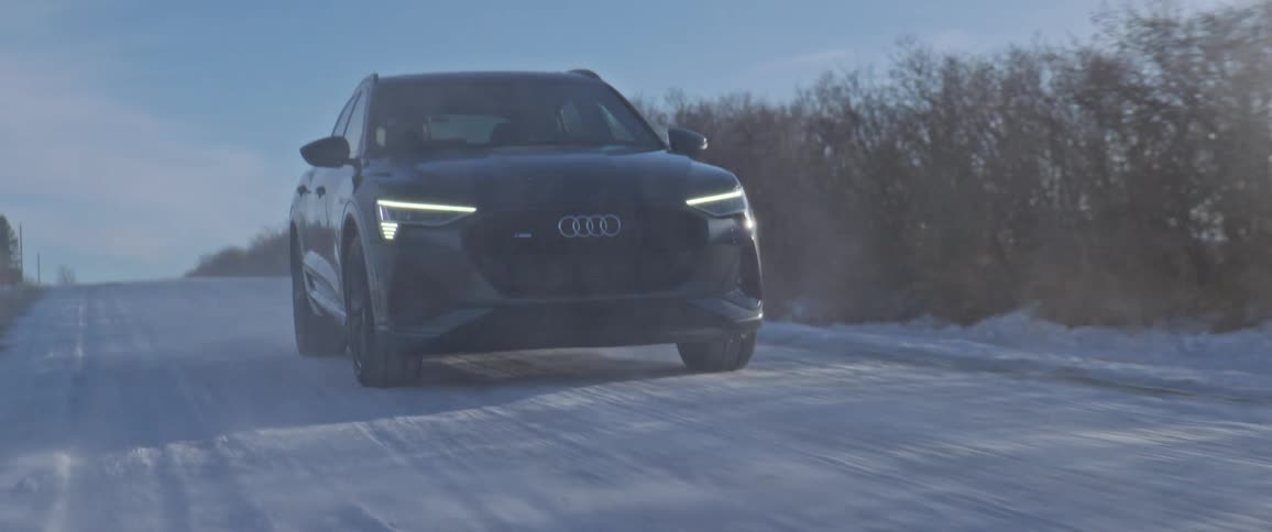 Black car driving on a snow covered road in the countryside at morning
