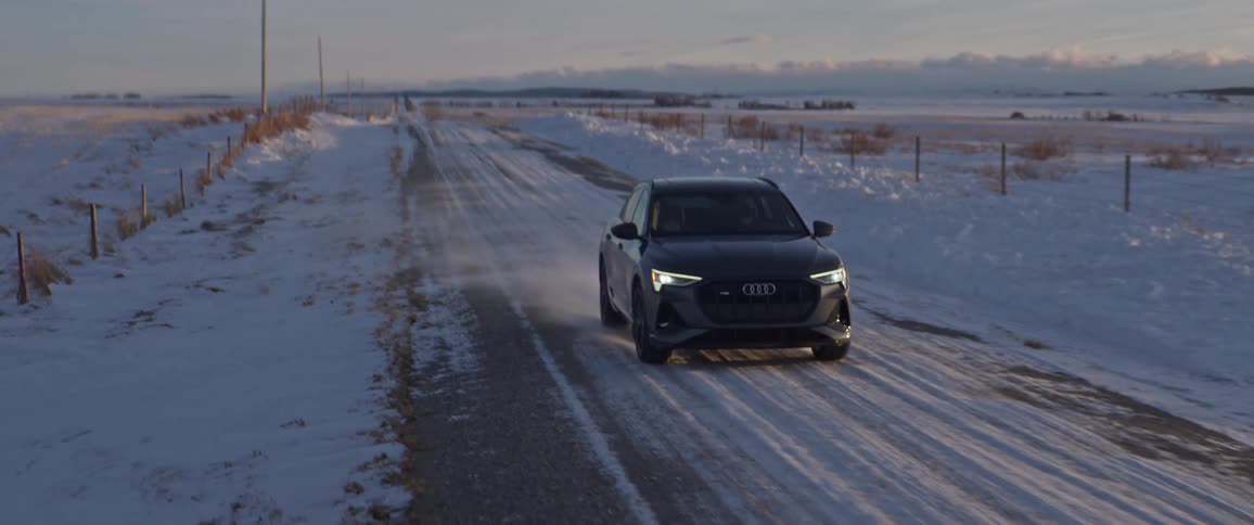 A black car travels on a snow covered road