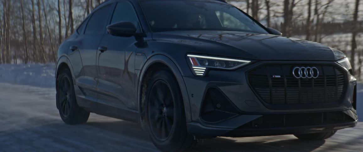 An audi vehicle drives on a rural snow dusted road