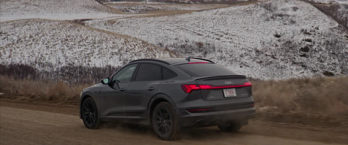 A car speeds along a dirt road that is surrounded by snow covered landscapes