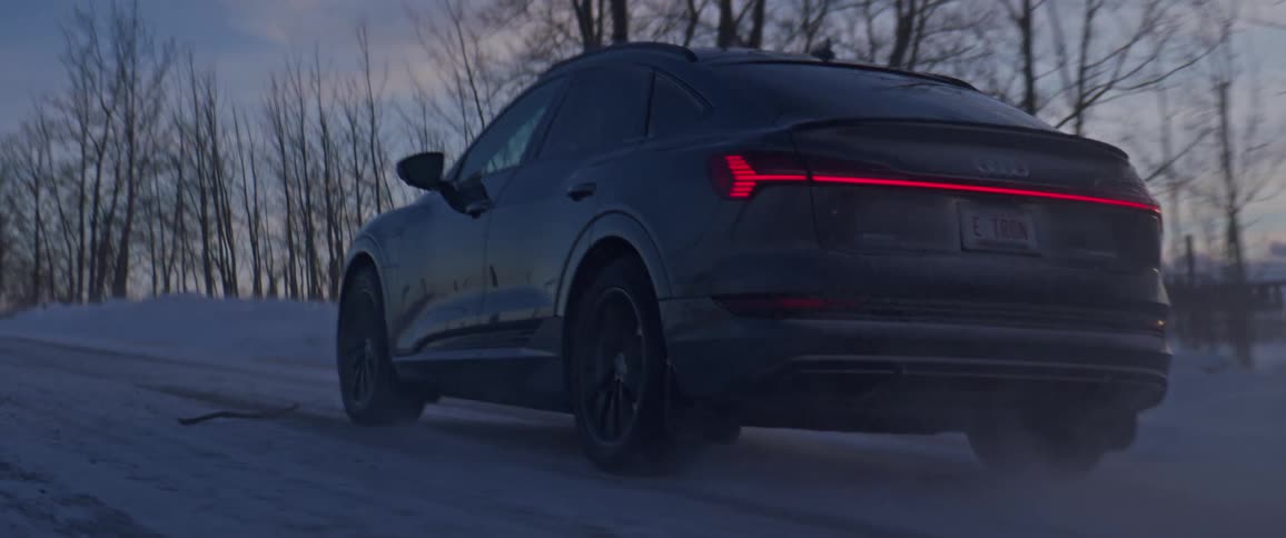 Black car driving on a snow covered road in the countryside at morning
