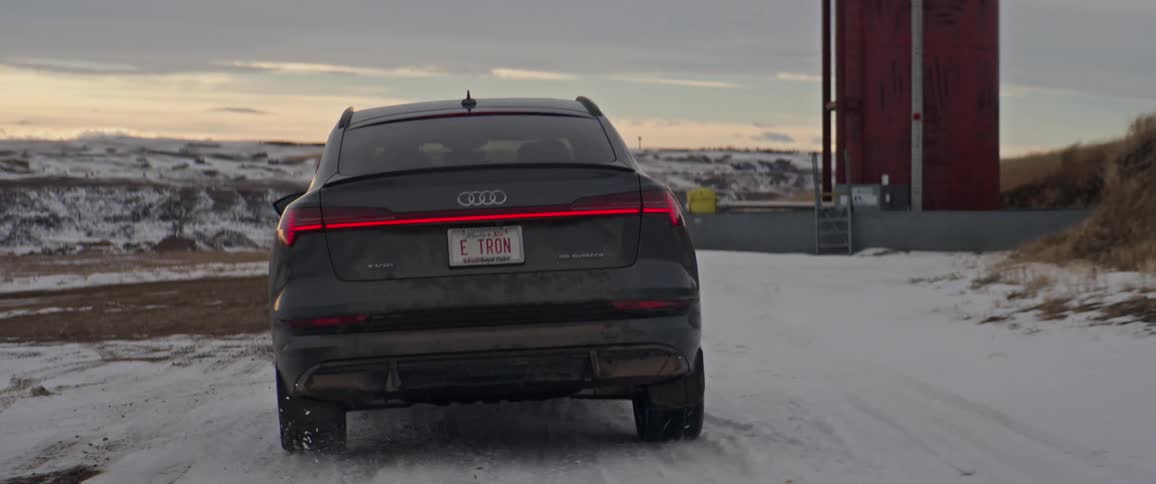Black car driving on a snow covered road in the countryside at morning