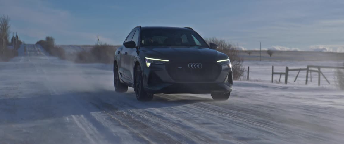 Black car driving on a snow covered road in the countryside at morning
