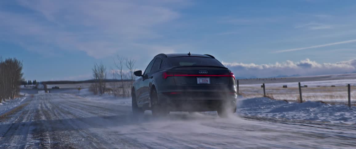 A vehicle drives on a snow dusted rural road