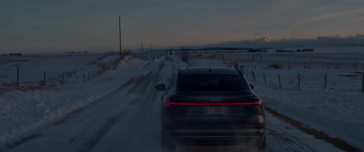 A car is driving on a rural road in winter