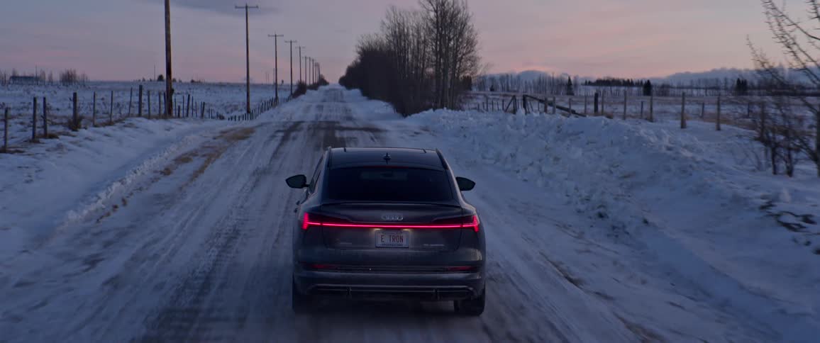A vehicle drives on a snow dusted rural road