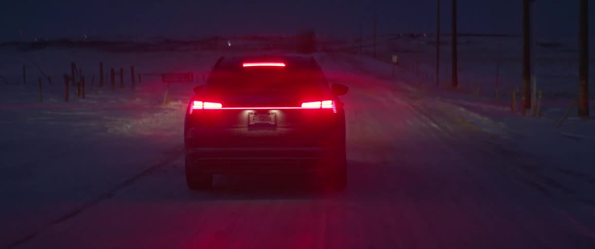 A car is driving on a road in winter at night