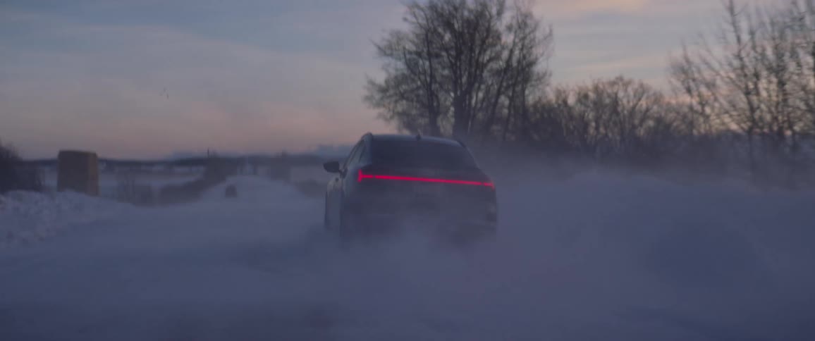 Black car driving on a snow covered road in the countryside at morning